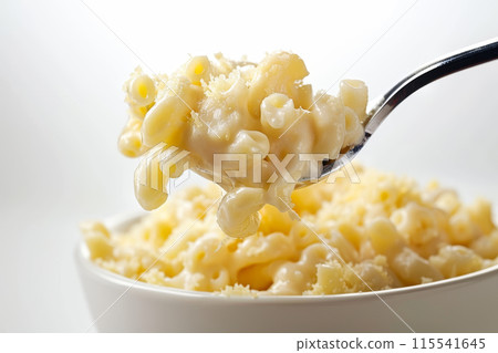 A spoonful of macaroni and cheese is being lifted from a bowl 115541645