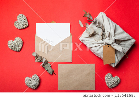 Zero waste Valentine's Day concept and mock up on red. Eco-friendly gift cloth wrapping in Furoshiki style, craft paper envelope,empty greetings card. Top down view or flat lay. Copy space for design Zero waste Valentine's Day concept and mock up on red. Eco-friendly gift cloth wrapping in Furoshiki style, craft paper envelope,empty greetings card. Top down view or flat lay. Copy space for design 115541685