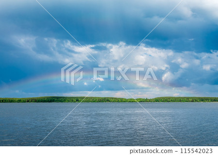 Rainbow over Blue lake with cloudy sky 115542023