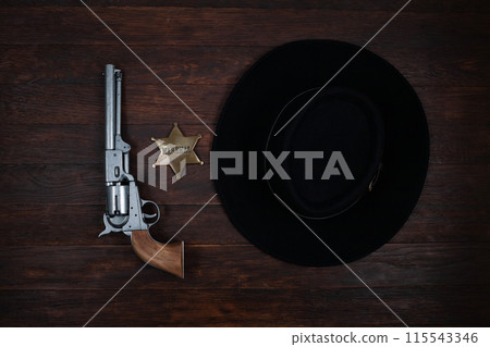 Old west gun, marshal star and hat on table. Top view. Old west gun, marshal star and hat on table. Top view. 115543346