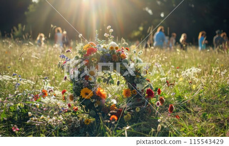 Wildflowers wreath on a sunny meadow. Sunny green natural background. Summer solstice concept. Symbol of Beltane. Wildflowers wreath on a sunny meadow. Sunny green natural background. Summer solstice concept. Symbol of Beltane. 115543429