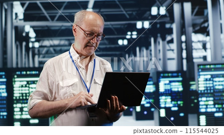 Proficient IT professional navigating network of servers in industrial establishment. Programmer with laptop in hand ensuring seamless operations, doing optimizations and maintenance in data center Proficient IT professional navigating network of servers in industrial establishment. Programmer with laptop in hand ensuring seamless operations, doing optimizations and maintenance in data center 115544025