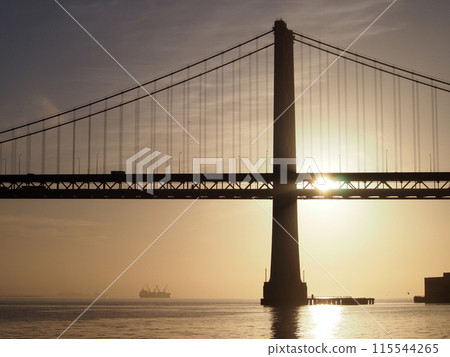 Sunrise over San Francisco Bay and through the Bay Bridge with boats in the water 115544265