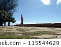 Man Handstanding stone foundation along cliff shore next to shallow ocean 115544629