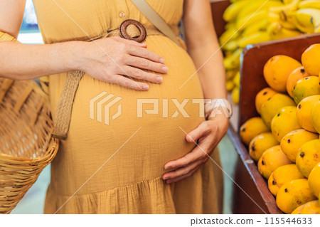 A pregnant woman is at a fruit stand in a grocery store Pregnant woman buying organic vegetables and fruits at Mexican style farmers market 115544633