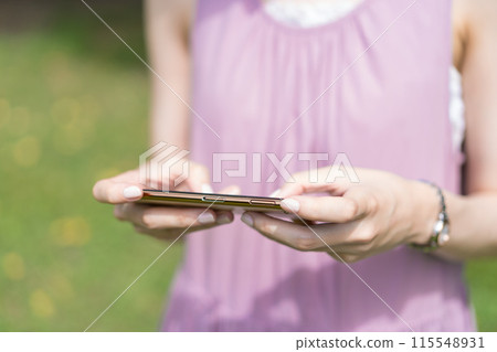 A young lady playing a game on a smartphone 115548931