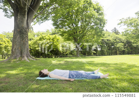 睡在瑜珈墊上的年輕女子接地，戶外瑜珈形象 115549881