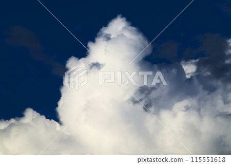 A cumulonimbus cloud has appeared in the blue sky and is growing large and ominously. 115551618