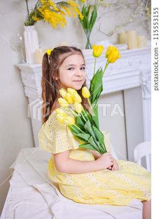 A cute girl in a yellow dress with a bouquet of yellow tulips against the background of bouquets of yellow tulips. A cute girl in a yellow dress with a bouquet of yellow tulips against the background of bouquets of yellow tulips. 115553155