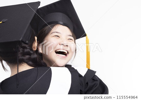 Happy high school girl friend graduates hugging in cap and gown 115554964