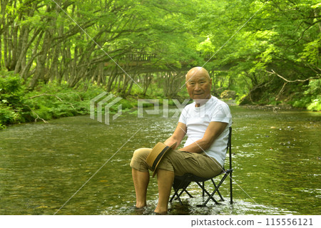 Senior man enjoying the coolness of a mountain stream in summer Senior man enjoying the coolness of a mountain stream in summer 115556121