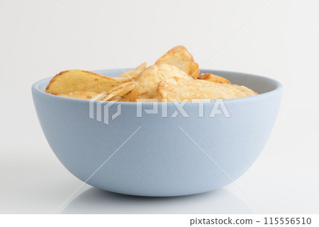 Organic potato chips in blue bowl isolated on white Organic potato chips in blue bowl isolated on white 115556510