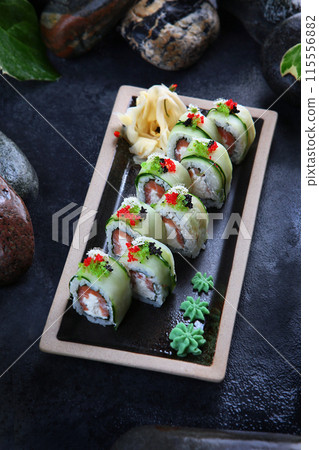 Rolls with salmon and butter cream. Dark background. Vertical photo. A traditional Japanese dish. 115556882