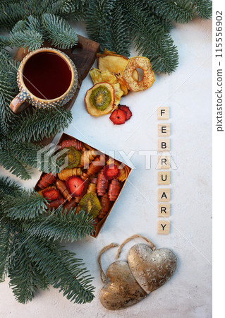 Ceramic cup with tea and fir branches. Box with handmade pastille. Sweet treat.Concept of New Year's card. Word February is made of wooden letters. Top view. 115556902