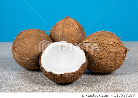 Whole coconuts and half a coconut on a blue and gray background close-up Whole coconuts and half a coconut on a blue and gray background close-up 115557197