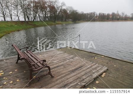 A rest bench stands on the river pier. 115557914