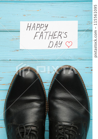 Happy Fathers Day message and black shoes on blue wooden background. 115561095