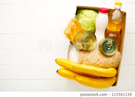 Donation box with food on white wooden background Donation box with food on white wooden background 115561139