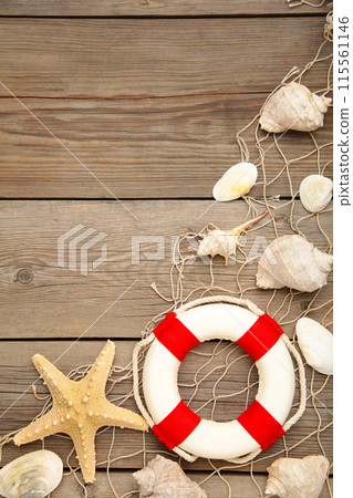 Red-white lifebuoy with sand and seashells on grey wooden background 115561146