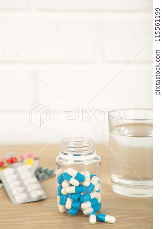 Bottle of pills and water on light background. Vertical foto Bottle of pills and water on light background. Vertical foto 115561199
