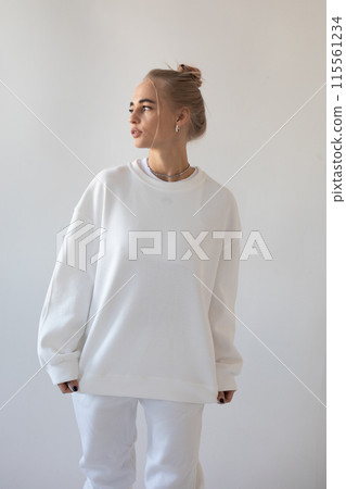 Beautiful blonde girl in a white hoodie and tights posing on a white background 115561234