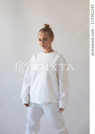 Beautiful blonde girl in a white hoodie and tights posing on a white background 115561242