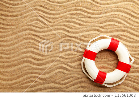 Red-white lifebuoy on sand. Summer concept with copy space Red-white lifebuoy on sand. Summer concept with copy space 115561308