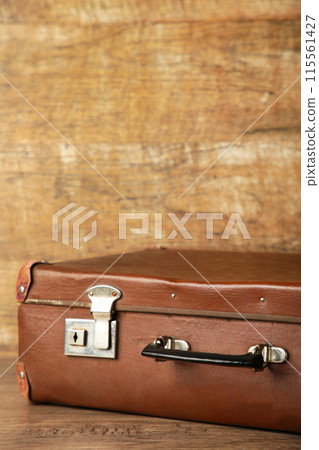 Old shabby leather portable suitcase for travel trip on brown background with copy space 115561427