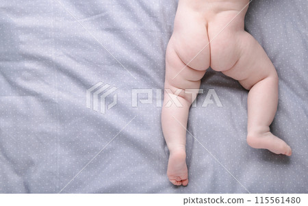 Small cute baby legs on grey bed Small cute baby legs on grey bed 115561480
