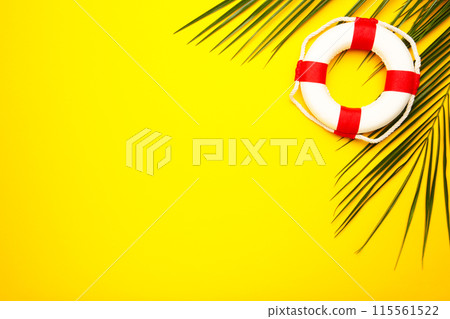 Red-white lifebuoy with palm leaf on yellow background 115561522