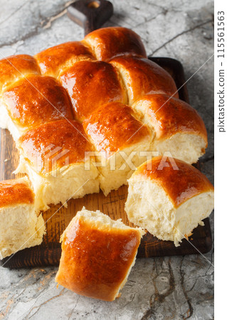Hawaiian sweet rolls, portuguese sweet bread, soft and stretchy buns closeup on the wooden board. Vertical 115561563