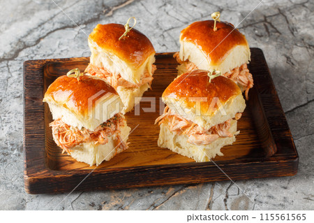 Butter Hawaiian rolls baked with pulled chicken and cheese close-up on a wooden board. Horizontal Butter Hawaiian rolls baked with pulled chicken and cheese close-up on a wooden board. Horizontal 115561565