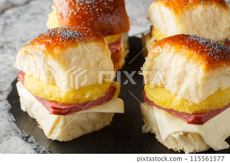 Hawaiian roll ham cheese pineapple closeup on a slate board. Horizontal Hawaiian roll ham cheese pineapple closeup on a slate board. Horizontal 115561577