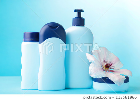 Blue cosmetic bottles with flowers on blue background. Top view Blue cosmetic bottles with flowers on blue background. Top view 115561960