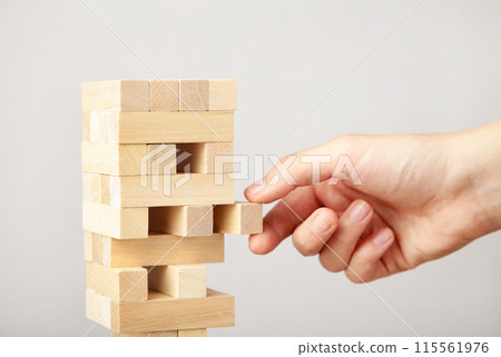 Business woman hand pick and put last piece block of the wood puzzle. Wooden block on grey background Business woman hand pick and put last piece block of the wood puzzle. Wooden block on grey background 115561976