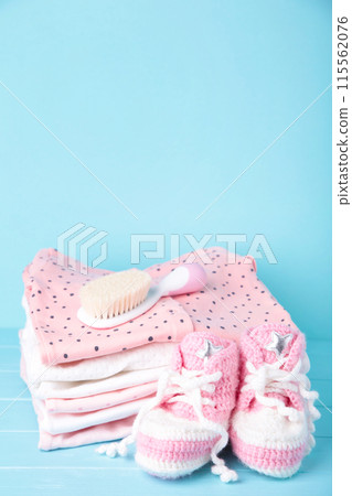 Baby clothes with booties and comb on blue background 115562076