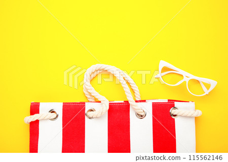 Summer bag with sunglasses on yellow background. Beach accessories Summer bag with sunglasses on yellow background. Beach accessories 115562146