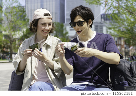 Inbound: A couple of foreign tourists eating rice balls sitting in the square in front of Tokyo Station 115562191