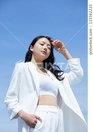 在天空背景下拍攝的一位身穿白色夾克的年輕女子的肖像 在天空背景下拍攝的一位身穿白色夾克的年輕女子的肖像 115562225