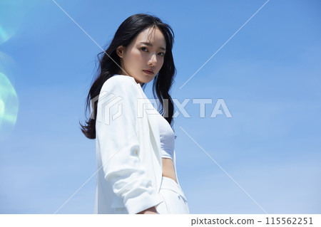 在天空背景下拍攝的一位身穿白色夾克的年輕女子的肖像 在天空背景下拍攝的一位身穿白色夾克的年輕女子的肖像 115562251