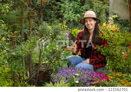 smiling young woman gardener holding shovel and rake in the garden smiling young woman gardener holding shovel and rake in the garden 115562701