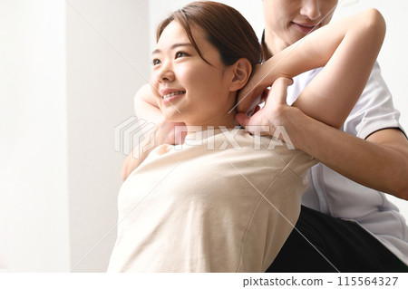 A man giving a massage to a female patient 115564327