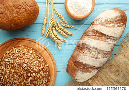 Fresh dark bread with spikelet of wheat on the blue wooden table 115565378