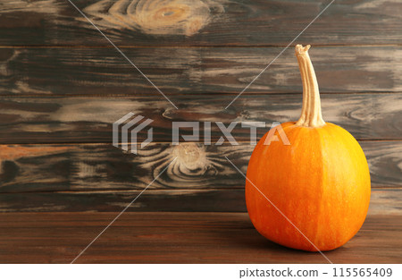 Fresh orange pumpkin on brown wooden background 115565409