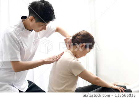 一名男子正在為一名女病人進行按摩治療 一名男子正在為一名女病人進行按摩治療 115566033