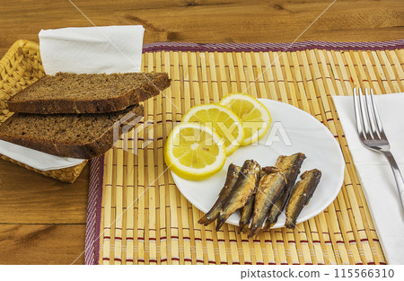 Breakfast of sprats with lemon and fresh brown bread 115566310