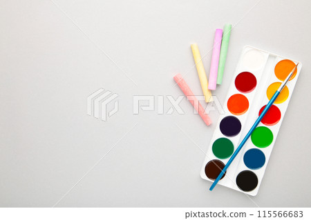Watercolor paints set with brushes and crayons for drawing on grey background 115566683