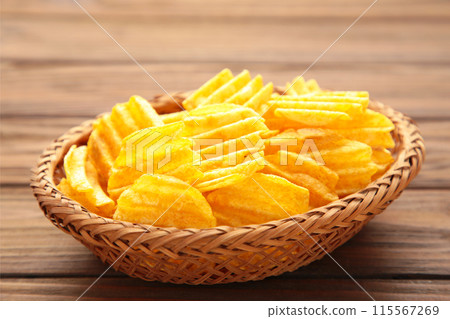 Potato chips in basket on brown wooden background. Potato chips in basket on brown wooden background. 115567269