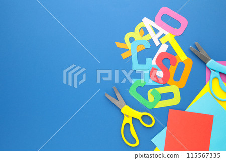 Scissors and colored paper for children's art on blue background Scissors and colored paper for children's art on blue background 115567335