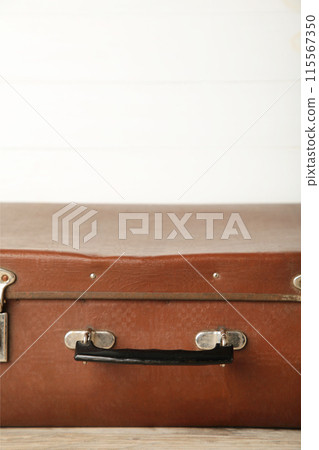 Vintage leather suitcase on light wooden background 115567350